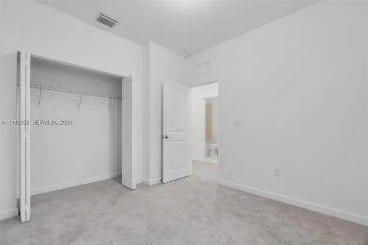 Neutral wall color, wall-to-wall carpeting, bi-fold closet doors with built-in shelving, and solid-core interior doors