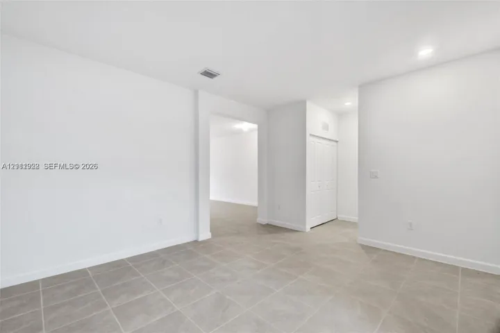 Neutral-toned tile flooring, recessed ceiling lighting, and built-in closet with multi-panel doors