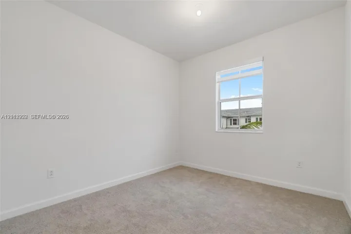 Neutral-toned interior room featuring wall-to-wall carpeting, white walls, and a single-hung window with fitted blinds
