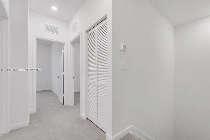 Interior hall featuring wall-to-wall carpeting, recessed ceiling lighting, and a closet with louvered double doors