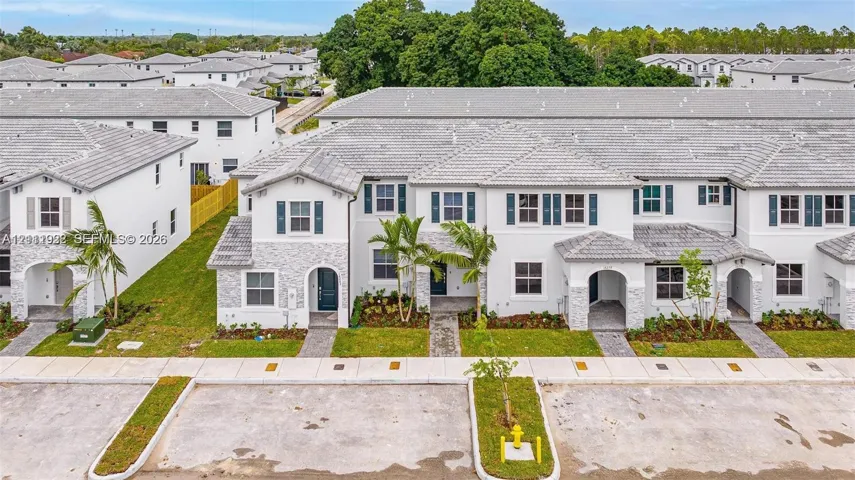 Multi-unit residential complex featuring stucco siding, stone veneer accents, concrete tile roofing, and decorative exterior shutters