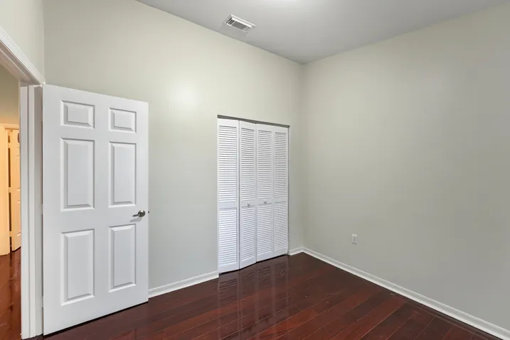 High ceilings, wood-finish flooring, and white louvered bifold closet doors