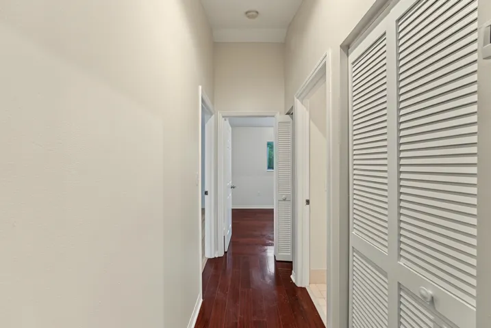 Hallway featuring high ceilings, wood-finish flooring, and white louvered closet doors