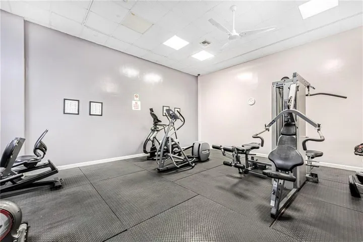 Fitness room featuring resilient rubber flooring, recessed overhead lighting, and a white ceiling fan