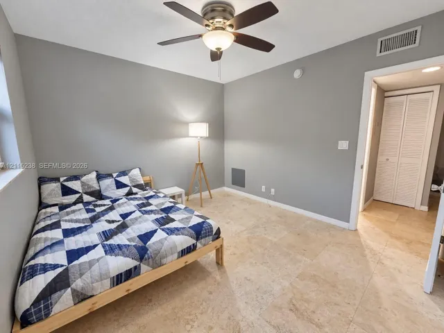 Neutral-toned room featuring large-format stone flooring, a ceiling fan with integrated lighting, and a closet with louvered doors