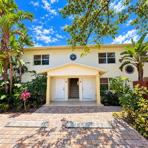 Stucco exterior with a covered entryway, paved brick driveway, decorative wall medallions, and an octagonal accent window