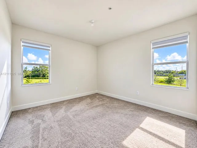 Neutral-toned interior space featuring neutral wall-to-wall carpeting, dual windows, and recessed ceiling lighting