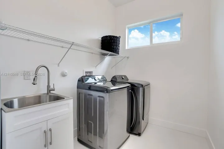 Laundry room featuring a stainless steel utility sink with a high-arch pull-down faucet, white shaker-style cabinetry, a horizontal sliding window, and wire shelving