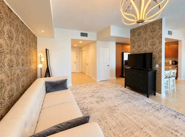 Living area featuring decorative patterned wall coverings, a large sculptural multi-arm chandelier, and tile flooring