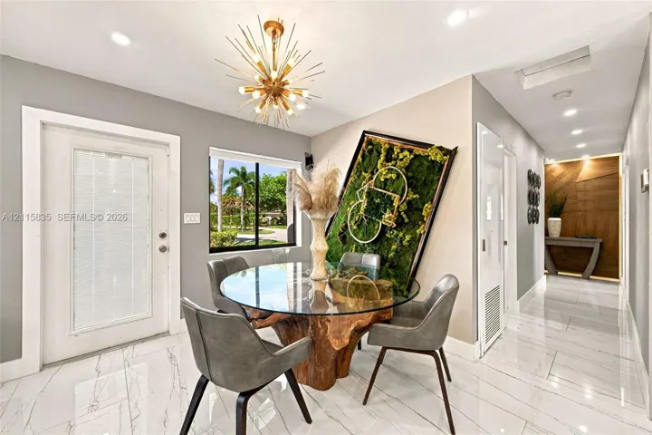 Entryway featuring white-veined tile flooring, a metallic sunburst chandelier, recessed lighting, and a wood-paneled accent wall