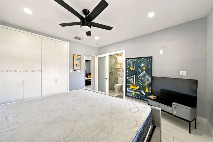 Full-height white cabinetry with recessed pulls, matte black five-blade ceiling fan, recessed lighting, and tile flooring