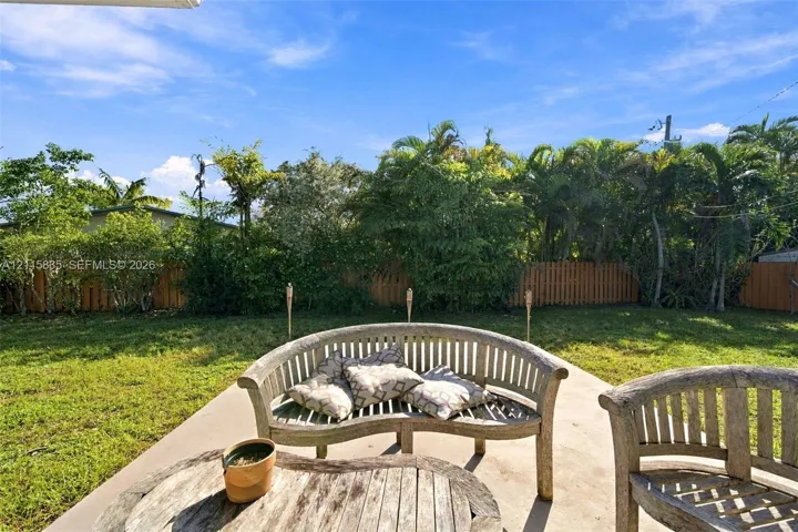 Backyard featuring a concrete patio, wood-slat perimeter fencing, and mature trees