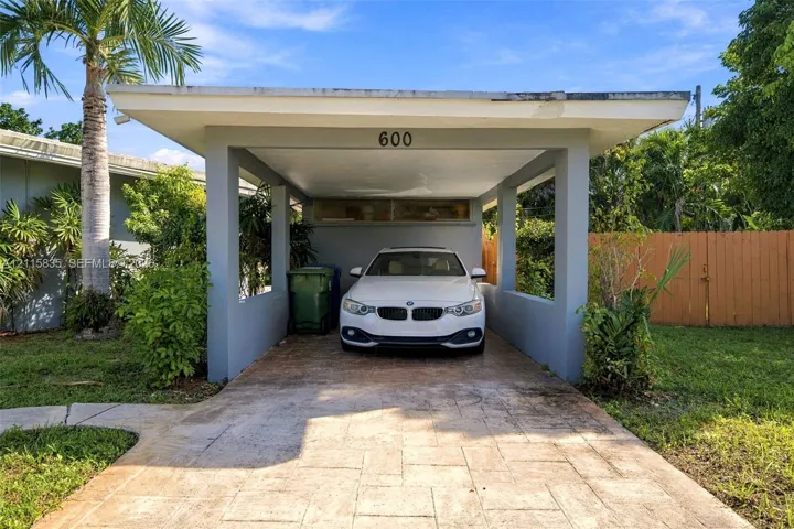 Covered carport featuring a concrete paver driveway, flat roofline, and integrated horizontal clerestory window