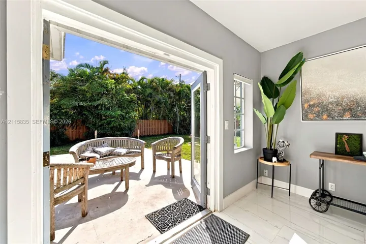 French doors opening to a concrete patio, stone-finish flooring, and a fenced backyard