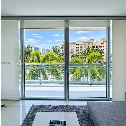 Floor-to-ceiling sliding glass doors, tiled balcony with glass railing, and large-format porcelain tile flooring