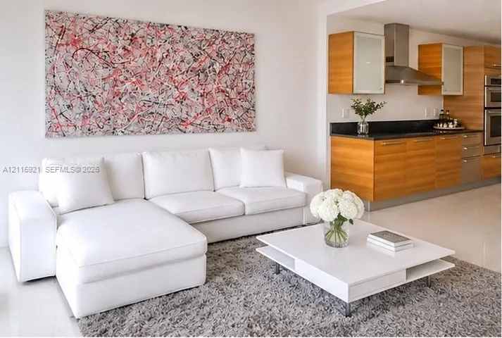 Kitchen featuring wood-finish cabinetry, dark solid-surface countertops, and a stainless steel wall-mounted range hood