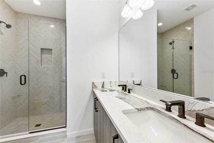 Primary bathroom with dual vanities and walk-in shower.