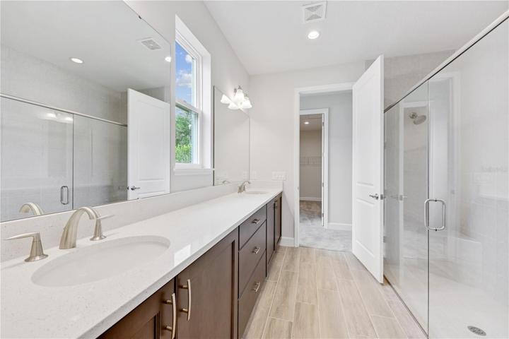 Primary bathroom with a dual sink vanity and large walk in closet