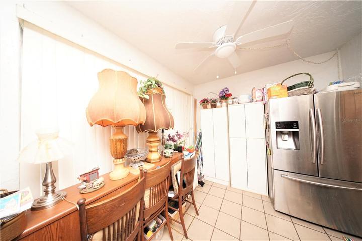 Inside of the Spacious FLoorida Room, Double-Door Stainless Steel Fridge, Windows that overlook park-like area with some trees, bench, and landscaping.