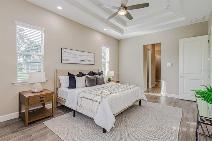 Master features elegant tray ceiling with crown molding and over bed lighting
