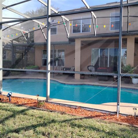 Back of house with screened-in pool and spa