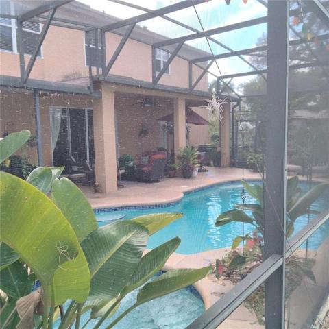 Back of house with screened-in pool and spa