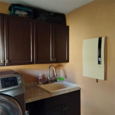 The utility room has a sink and storage cabinets and stainless steel washer and dryer