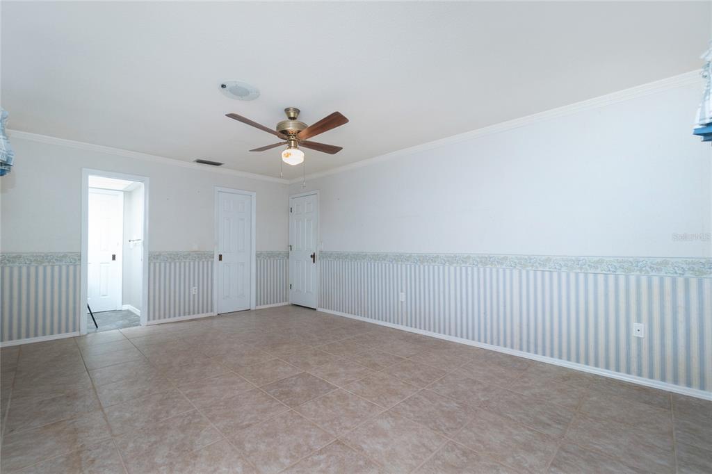 Guest bedroom #2 features a ceiling fan, crown molding and a wall closet.