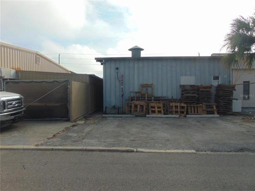 This is the rear of the spray painting booth with top vent and water suppression/hydrant. Left is storage area behind fence.