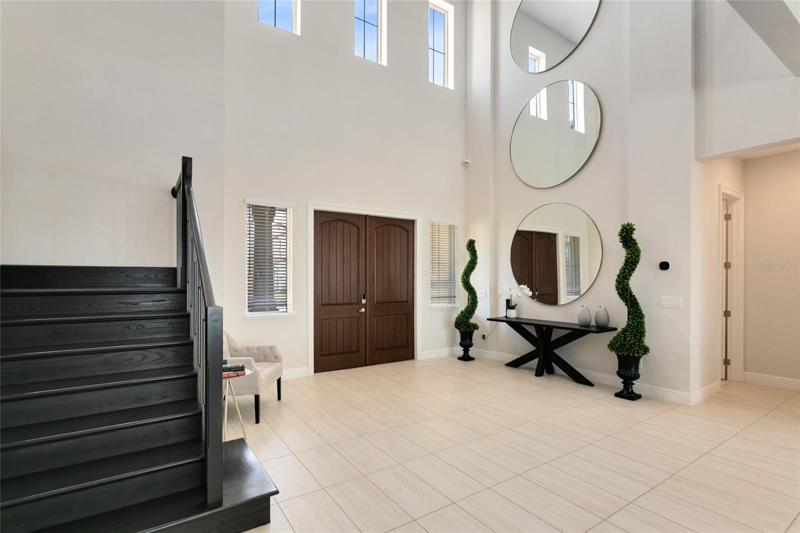 The grand double door entry welcomes you inside to the dramatic two story foyer with soaring ceilings.