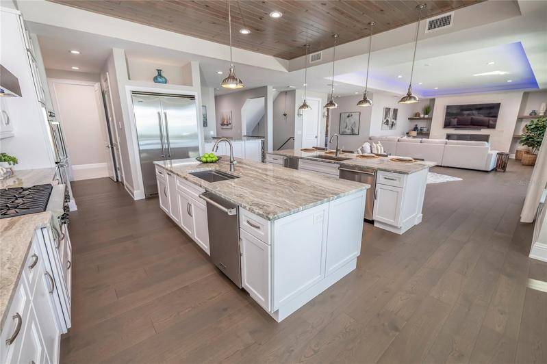 Kitchen boasts wood cabinets, quartz countertops. Viking natural gas cooktop with hood, two dishwashers, two ovens, icemaker, two stainless undermount sinks, and two garbage disposals.