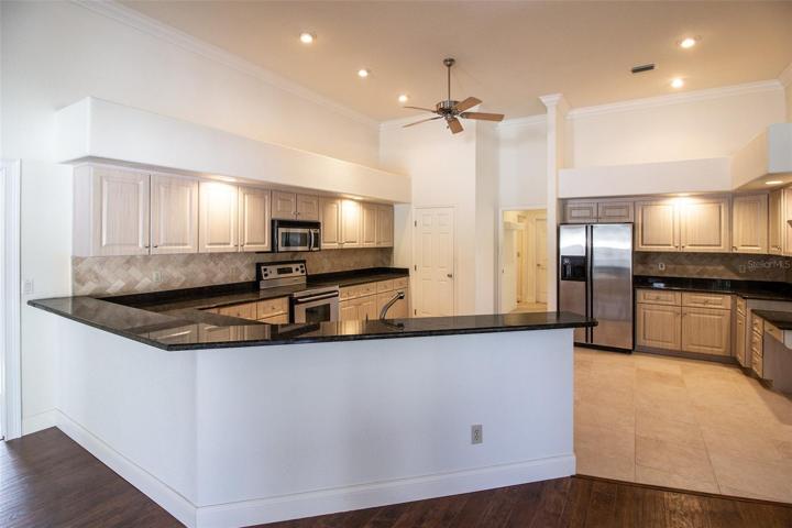 Kitchen has granite countertops, stainless steel appliances, lots of lighting and tile floors.