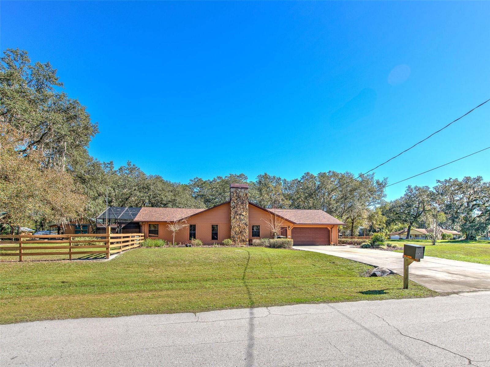 Side Driveway /Garage Entrance of Custom Home(3 Bed/3 Bath/2 Car Garage on 2.06 acres) NEW ROOF &amp; PAINT in 2022. Not in a Flood Zone, No HOA or CDD. Huge Pole Barn, Cowboy Kitchen, Fire Pit, Potting Shed, Vacant land &amp; Huge Screened in Lanai.