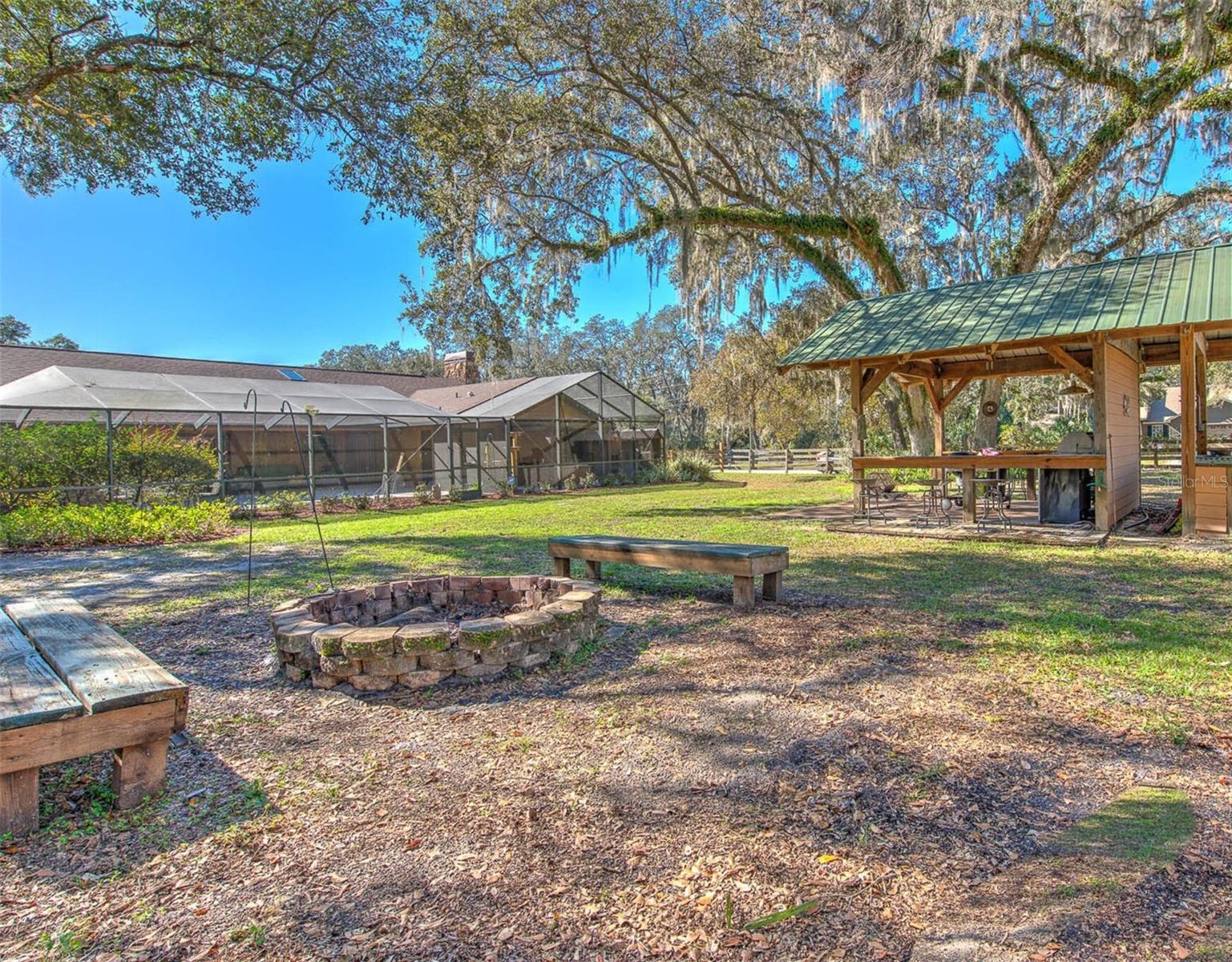 Tranquil Backyard view of the home, screen enclosure, fire pit, Cowboy kitchen and potting shed.