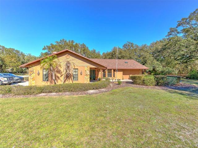 Front of Custom Home(3 Bed/3 Bath/2 Car Garage on 2.06 acres) NEW ROOF & PAINT in 2022. Not in a Flood Zone, No HOA or CDD. Huge Pole Barn, Cowboy Kitchen, Fire Pit, Potting Shed, Vacant land & Huge Screened in Lanai.