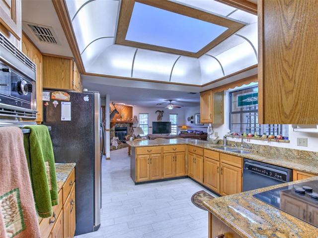 DAYTIME View of open kitchen with skylight, solid wood cabinets, granite countertops and window overlooking the lanai.