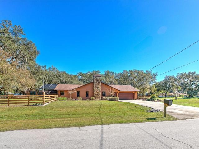 Side Driveway /Garage Entrance of Custom Home(3 Bed/3 Bath/2 Car Garage on 2.06 acres) NEW ROOF & PAINT in 2022. Not in a Flood Zone, No HOA or CDD. Huge Pole Barn, Cowboy Kitchen, Fire Pit, Potting Shed, Vacant land & Huge Screened in Lanai.
