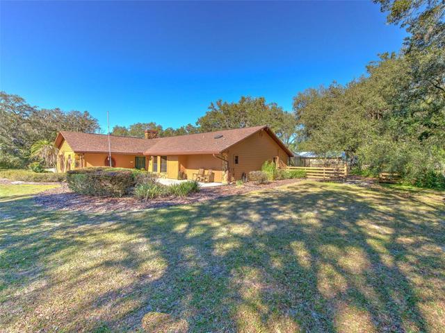 Side/Front View of Property. Custom Home(3 Bed/3 Bath/2 Car Garage on 2.06 acres) NEW ROOF & PAINT in 2022. Not in a Flood Zone, No HOA or CDD. Huge Pole Barn, Cowboy Kitchen, Fire Pit, Potting Shed, Vacant land & Huge Screened in Lanai.