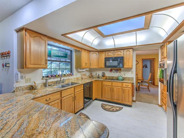 DAYTIME View of open kitchen with skylight, solid wood cabinets, granite countertops and window overlooking the lanai.