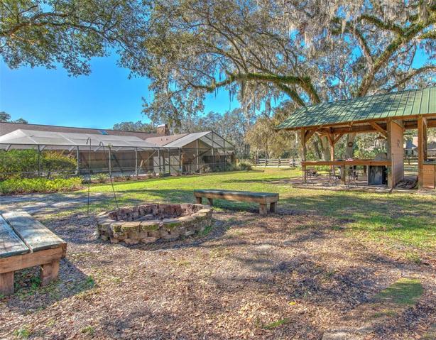 Tranquil Backyard view of the home, screen enclosure, fire pit, Cowboy kitchen and potting shed.