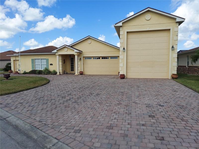 Front view of home with large area of driveway leading to garages and front   door. Notive the rain barrel downsots.