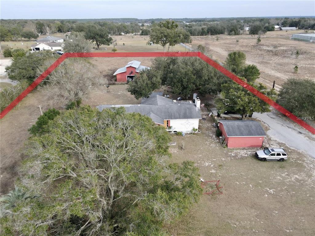 The lot features a paved driveway that leads to buildings.