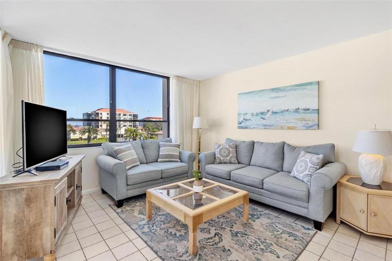 Cozy living room with huge double windows & tile floors for care-free maintenance.  Unit comes fully furnished with this coastal style furniture.
