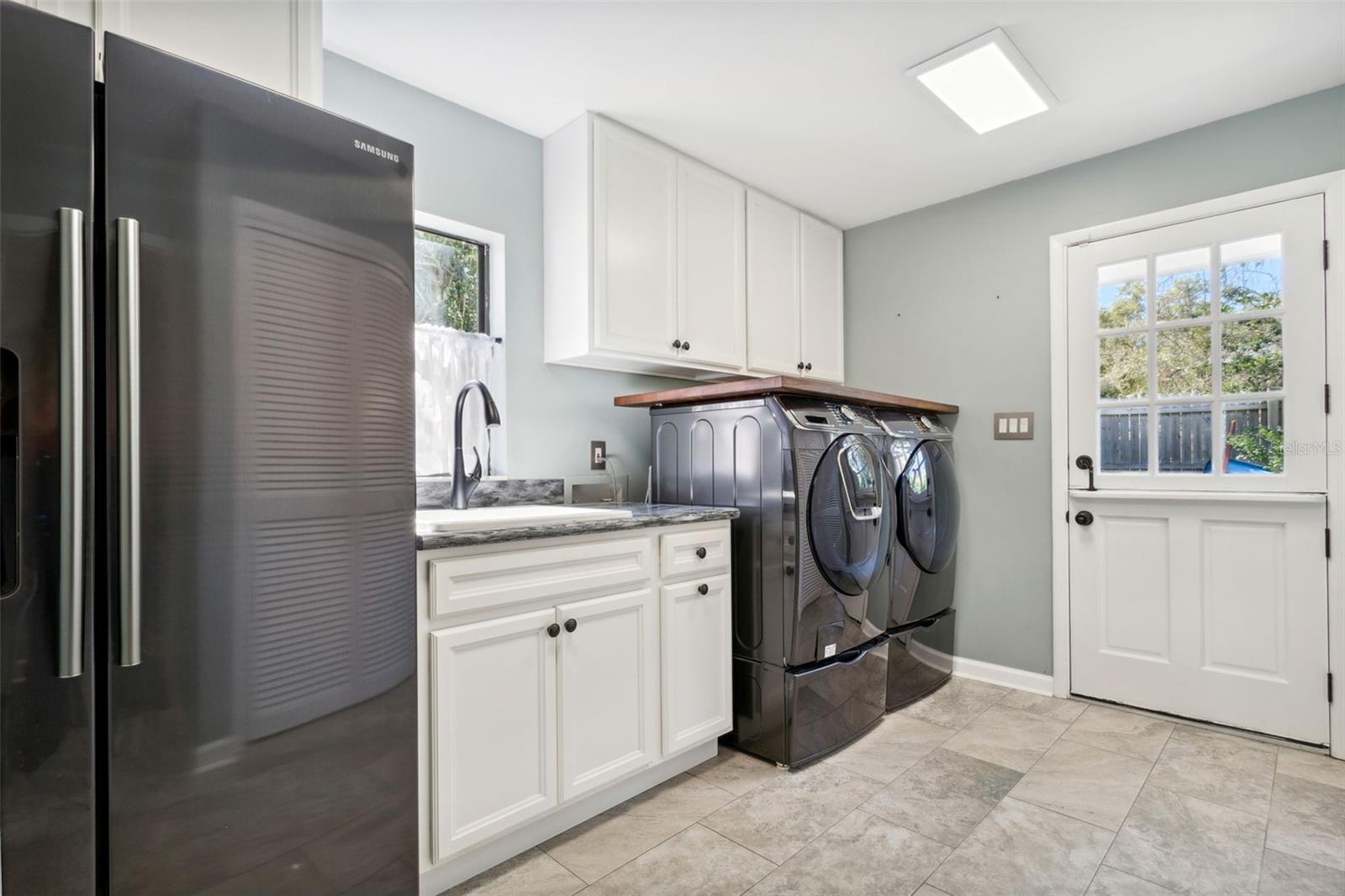 Large laundry room with secondary refrigerator and sink.