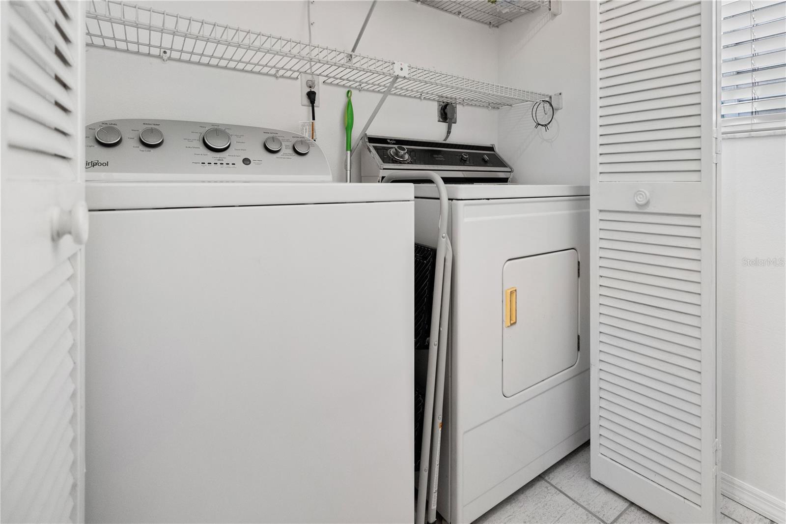 full size washer and dryer in the kitchen, with shelving for storage