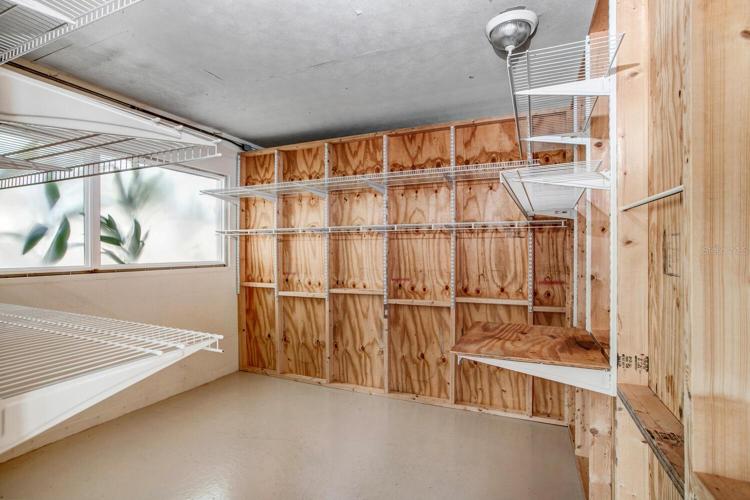 Inside the wooden, enclosed room, there's a large window and lots of storage shelves.