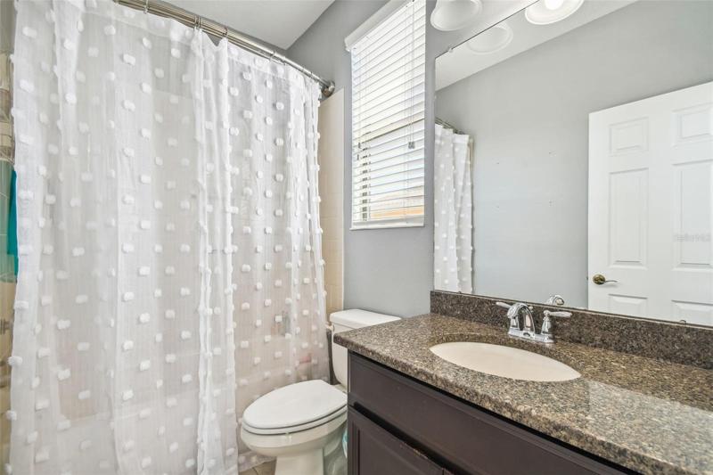 The bathroom in Bedroom 2 features a vanity with granite counter and a tub/shower.