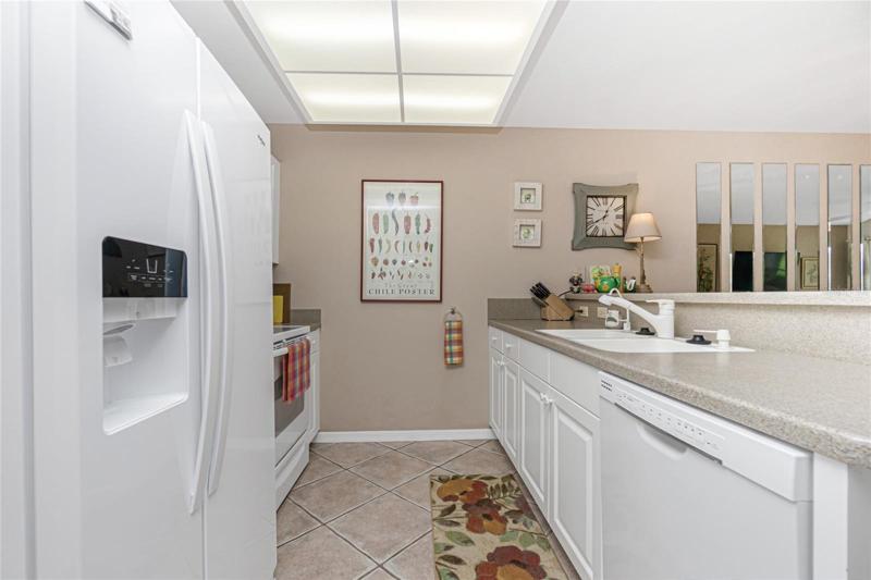 The kitchen features white raised panel cabinetry, solid surface countertops and integrated sink. 