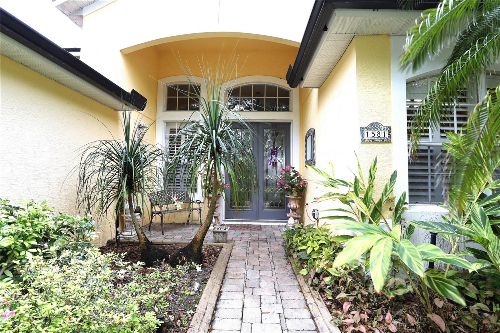 Front door, landscape includes pony palms, azaleas, ginger plants