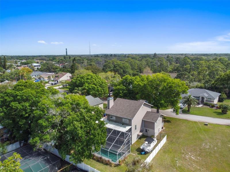 drone shot of back of home with vacant lot next door